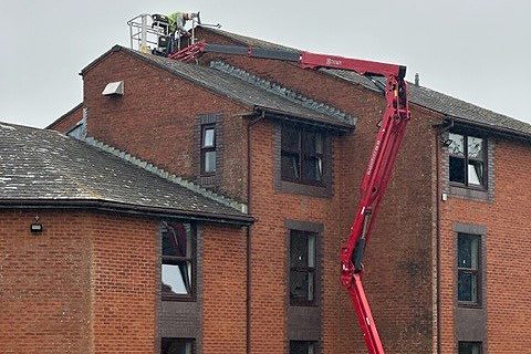 Hinowa 20.10 tracked spider platform reaching the roof of a four-storey brick building